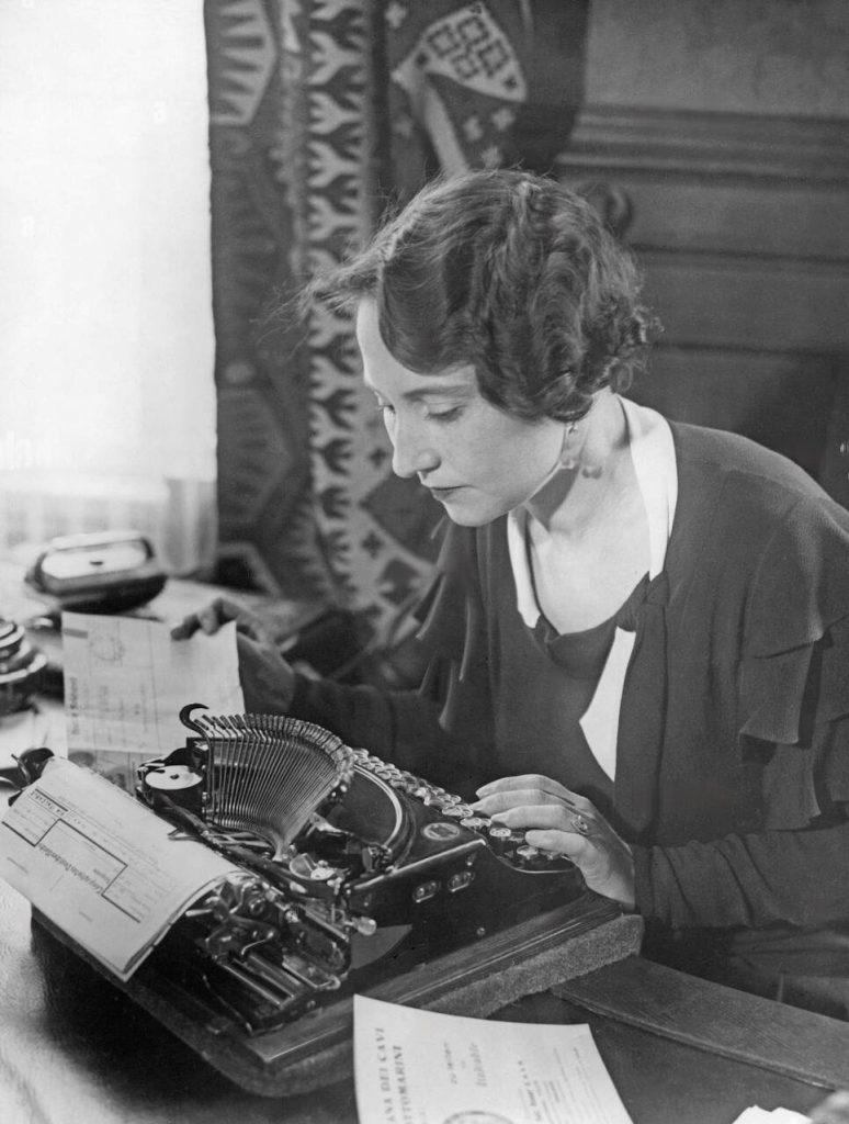 a female journalist sitting at a typewriter